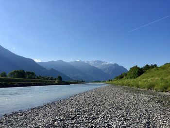 Scenic view of lake and mountains against clear blue sky