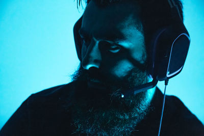 Close-up of man wearing headphones against colored background