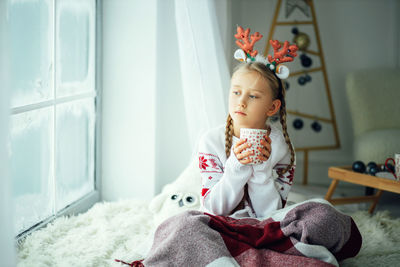 The girl at home looks at the snowfall, warm cozy day at home with tea