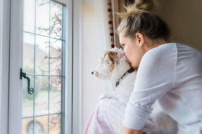 Side view of girl sitting by window