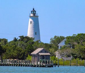 Lighthouse by building against clear sky