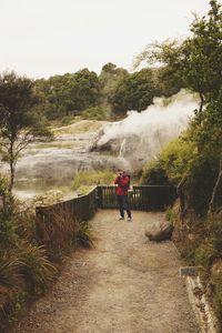 Man with red jacket in a park with a camera 