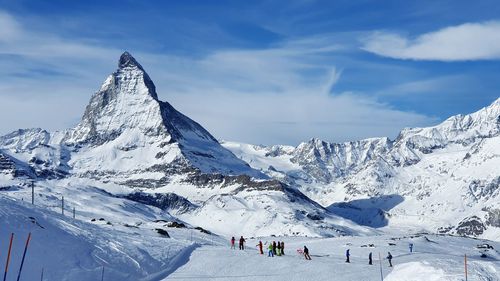 People on snowcapped mountains against sky