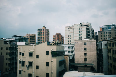 Buildings in city against cloudy sky