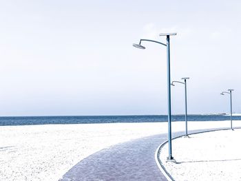 Street light by sea against sky during winter