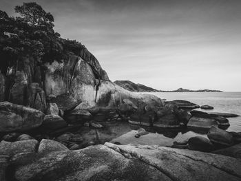 Rock formations on beach against sky