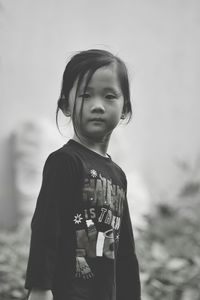 Portrait of young woman standing against wall