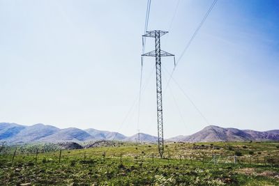 Low angle view of wind turbines on field against clear sky