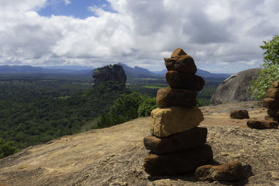 Stack of rocks on landscape against sky