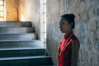 Side view of a woman looking away against wall