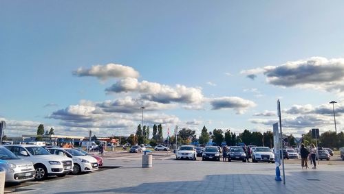 Cars parked on road against sky in city