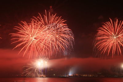 Firework display in sky over sea at night