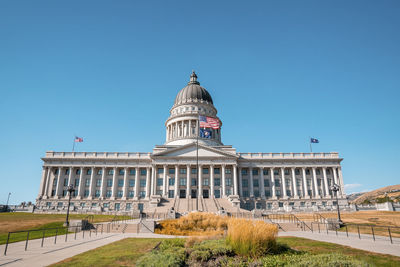 Garden at entrance of state capitol building with clear blue sky in background