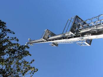 Low angle view of crane against clear blue sky