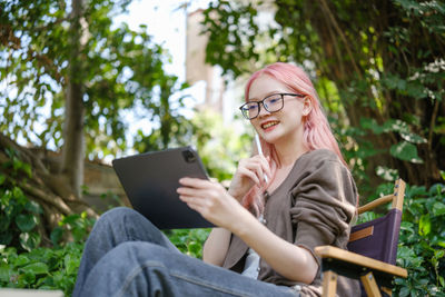 Young woman using mobile phone while sitting outdoors