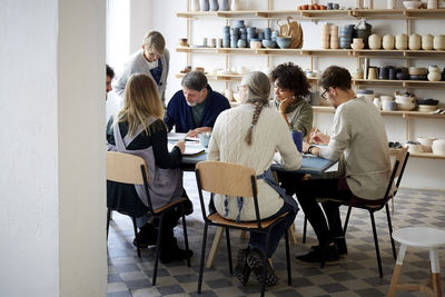 Female instructor examining drawing of students at table during art class