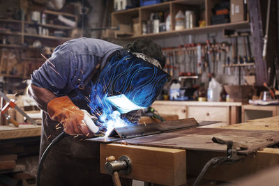 Manual worker welding metal at workshop