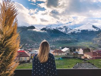 Rear view of woman standing by buildings against sky