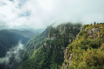 People on steep cliffs in fortaleza canyon with fog, near cambara do sul, brazil.