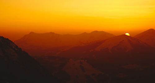 Scenic view of mountains against orange sky