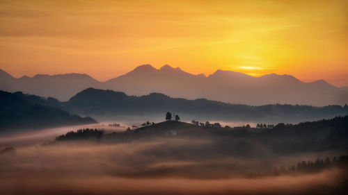 Scenic view of silhouette mountains against orange sky