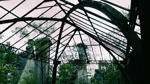 Low angle view of abandoned greenhouse against sky