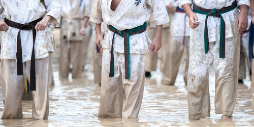 Midsection of people wearing karate belts standing in water