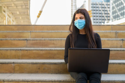 Midsection of woman using mobile phone while sitting on staircase