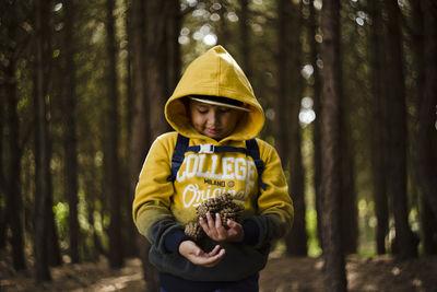 Full length of boy standing on tree trunk in forest