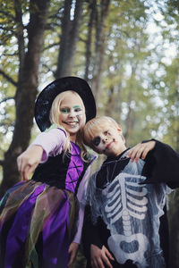 Happy halloween,funny kids brother and sister have fun in carnival costumes in the forest
