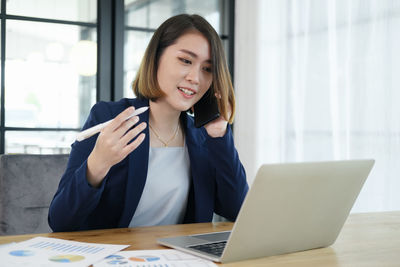 Young woman using phone while sitting on table