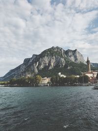 Scenic view of sea by mountain against cloudy sky