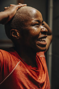 Happy female athlete with head in hands laughing at gym