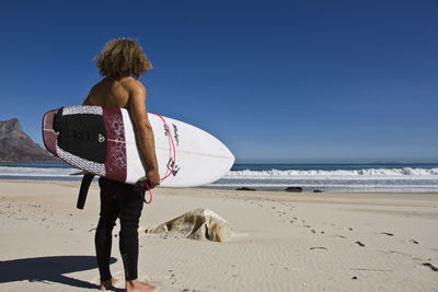 Rear view of woman walking on beach against clear sky