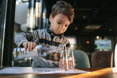 A little boy pours himself a glass of water from a bottle in a cafe. independence and maturity. 