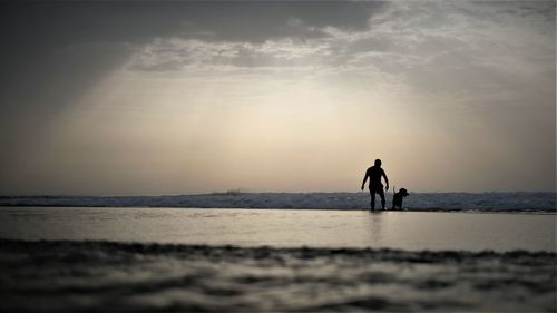 Silhouette men standing on beach against sky during sunset