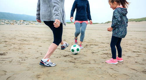 Low section of family playing with ball at beach