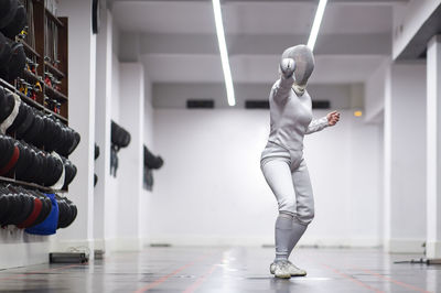 Woman in fencing outfit practicing at gym