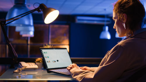 Side view of man using laptop at home