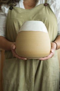 Midsection of woman holding ceramic in workshop