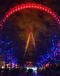 Illuminated ferris wheel against sky at night