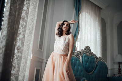 Young woman with arms outstretched standing against wall