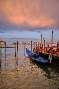 Wooden post in sea against sky during sunset