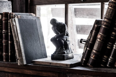 Close-up of figurine and old books on shelf