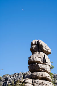 Low angle view of stone stack against blue sky