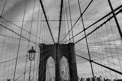 Low angle view of suspension bridge against cloudy sky