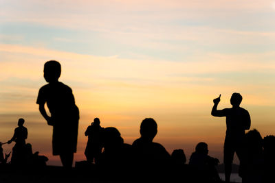 Silhouette people standing against sky during sunset
