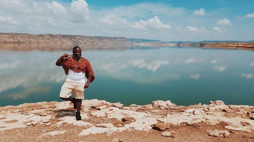 Man standing on one leg against lake