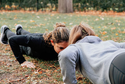 Rear view of friends lying on field during autumn