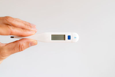 Close-up of hand holding camera over white background